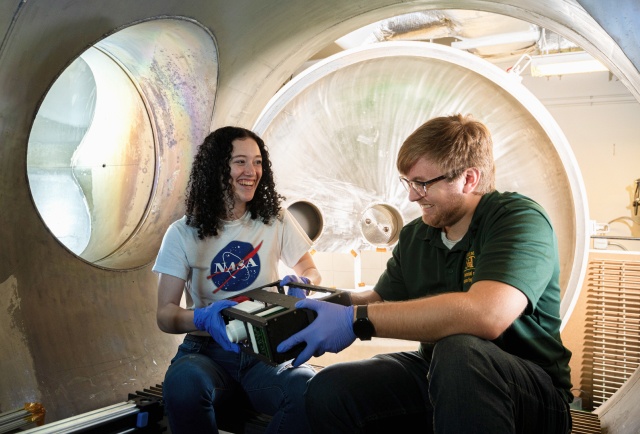 Two Mechanical and aerospace engineering undergraduates collaborate in the plasma vacuum chamber